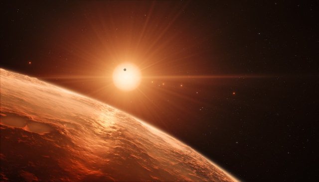 This artists impression shows the view from the surface of one of the planets in the TRAPPIST-1 system. At least seven planets orbit this ultra cool dwarf star 40 light-years from Earth and they are all roughly the same size as the Earth. They are at the right distances from their star for liquid water to exist on the surfaces of several of them.