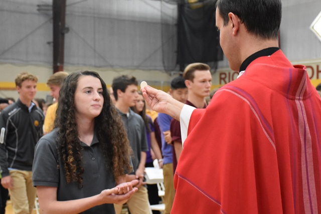 A member of the Class of 2021 receives communion from Fr. Carr.