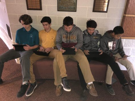 These juniors, like many others, pile up along the hallway by the business offices leading to the Chapel to use their iPads. 