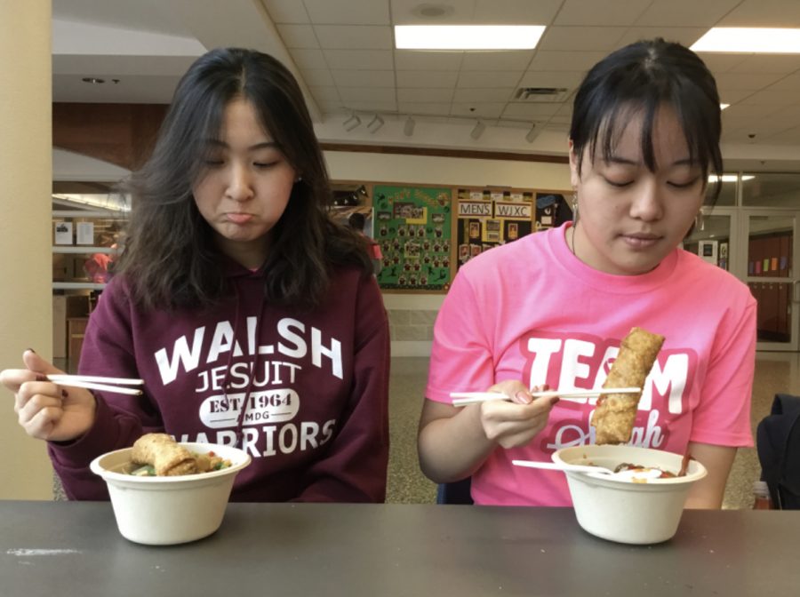 Seniors Jancy Zhang (left) and Phyllis Liu sit down with mixed reactions as they prepare to eat a meal with with chopsticks. 