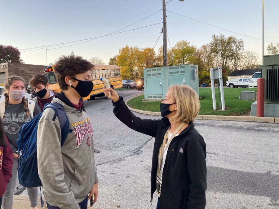 Every morning all students and adults of Walsh Jesuit are required to have a temperature check before entering the building. Mrs. April Katona, secretary to the principal, checks Jimmy Taylor ‘23.