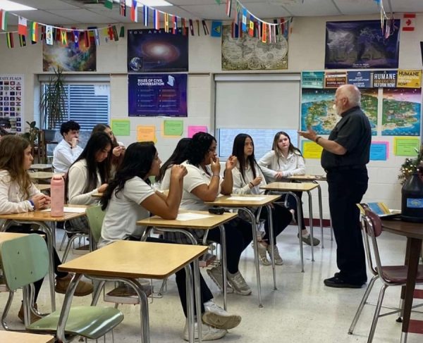 Fr. Pete Neeley, SJ, is talking about migration at the southern 
border to a group of students.