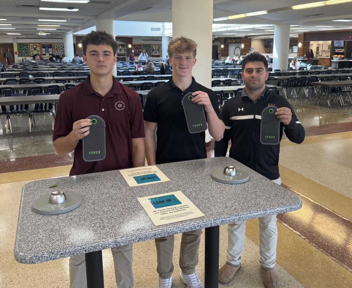 Seniors Sawyer Del Busso, Marty Tobin, and Vinnie Courtad (left to right) pose in the Commons at one of many unlocking stations around the school. 